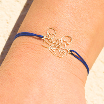 Bijou émotionnel porté au poignet, bracelet en or avec cordon bleu, sculpté à partir d’un souvenir de famille précieux.