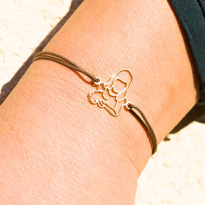 Bijou sur mesure Stydor porté au poignet, bracelet en or avec cordon taupe, façonné à partir d’une photo d’enfant.